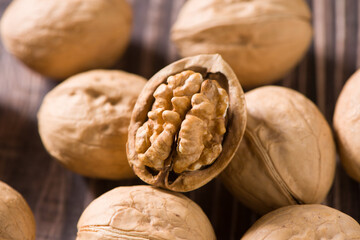 Walnut kernels and whole walnuts on wooden table.