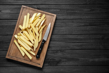 Cut raw potatoes on black wooden table, top view. Space for text