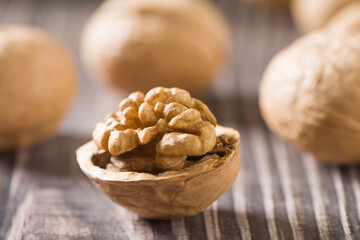 Walnut kernels and whole walnuts on wooden table.