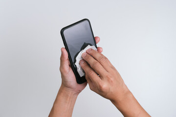 Hand wiping the mobile phone with the alcohol sanitiser wipes  to clean and prevent the spread of bacteria and virus.  Personal hygiene concept. Isolated white background