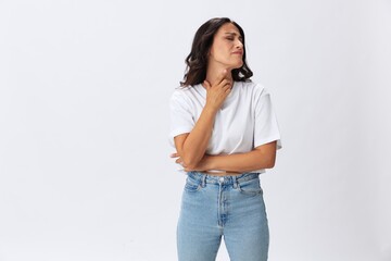 Woman sore throat and inflammation of the ligaments with a cold, a woman in a white t-shirt and jeans on a white background, copy space