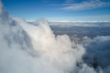 Aerial view from airplane window at high altitude of earth covered with puffy cumulus clouds forming before rainstorm