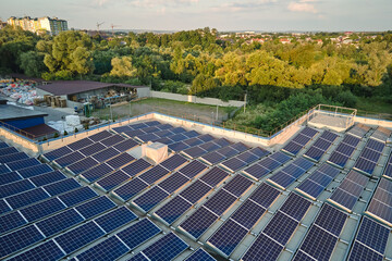 Aerial view of blue photovoltaic solar panels mounted on industrial building roof for producing...