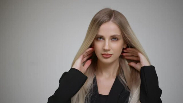 Slow motion of the long hair of a charming blonde. Grey background.