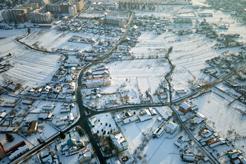 Aerial view of private homes with snow covered roofs in rural suburbs town area in cold winter