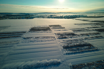 Aerial view of snow covered agricultural fields with barren surface in winter