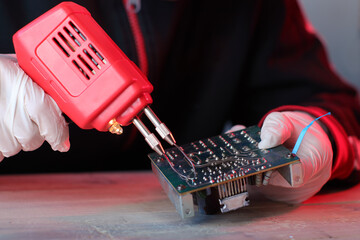soldering on the board a red transformer soldering iron by a person - 551950229