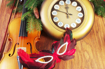 Violin, wall clock, carnival mask and Christmas decorations on wooden texture.
