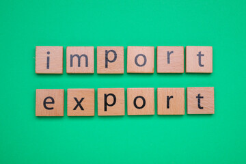 Words Import and Export made of wooden squares on green background, top view