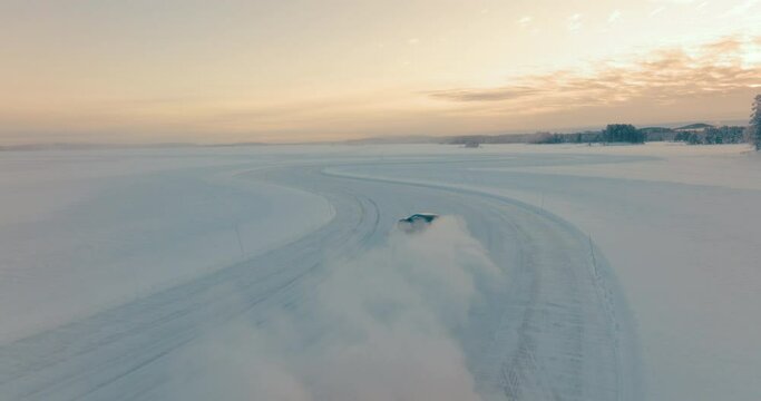 Chasing driver drifting corners on Lapland ice lake track at sunrise aerial view