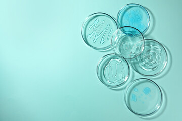 Petri dishes with liquids on turquoise background, flat lay. Space for text