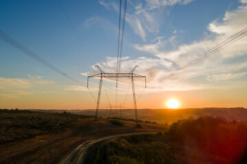 Dark silhouette of high voltage tower with electric power lines at sunrise. Transmission of...