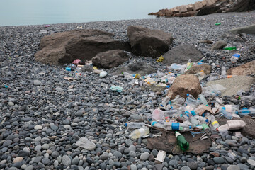 Garbage scattered on pebbles near sea. Recycling problem