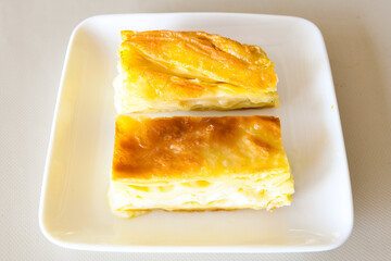Turkish style meat stuffed filo dough borek served kol boregi. Cheese and minced pie are sliced on a marble background. Turkish name: Kol Boregi, kiymali, peynirli su boregi.