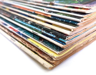 Closeup of a stack of vintage comic books with faded and worn pages isolated on white background