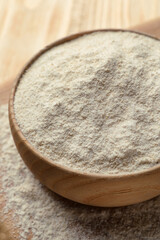 Quinoa flour in bowl on wooden table, closeup