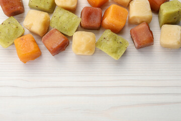 Different frozen fruit puree cubes on white wooden table, flat lay. Space for text