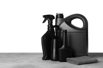 Bottles, canister and car wash cloth on grey table against white background