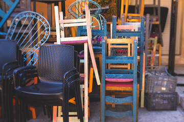 Chairs piled up in empty cafe, the end of touristic season, closed restaurant in the european streets, bad season, end of working hours, seats stacked in after hours, restaurant went bust bankrupt