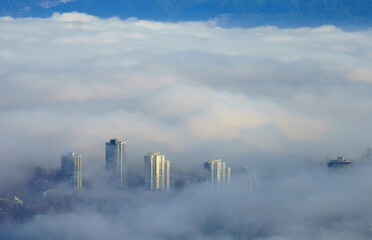 High-rise buildings, partially obscured by a low-lying cloud inversion, a common occurrence in BC during cold winter weather.