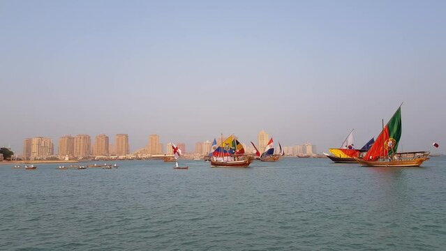 Qatar flag sail waving in the wind on a traditional boats lenj near the sea gulf during the fifa world cup doha in asia host football teams and match tournoments to the final game. Doha cityscape day.