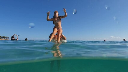 Father has fun by throwing his daughter into tropical sea water and making her jump. Slow motion half underwater pov