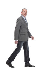 side view full length photo of a mid aged business man walking forward and looking at camera.