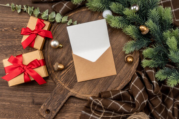 Greeting card on wooden cutting board with Christmas decorations.