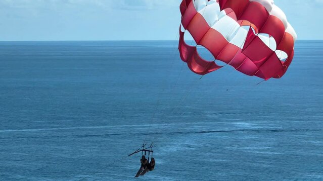 Aerial view following parasailers in sunny Cancun, Mexico - zoomed crop, drone shot