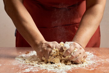 Pastry chef preparing flour dough for cookies. Hands preparing the bread dough on a table.