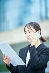 スマートフォンで通話するスーツ姿の若い女性