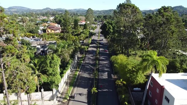vista de drone sobre la calle principal de jarabacoa con algunos autos transitando en la via, hermoso dia solea y verde vegetacion.