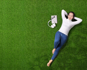 Top view of Asian woman closed the eyes lying on short grass.