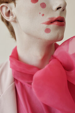 Close up shot of lower face and neck of young man wearing freaky make-up with pink bow