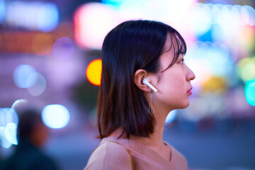 夜の繁華街に立つ若い女性