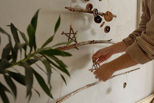 Unrecognizable man decorating wall in his house with handmade Christmas tree and toys