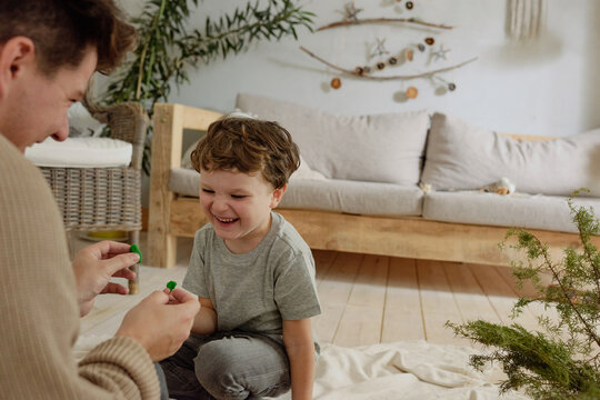 Father and son having fun playing with kinetic sand sitting in front of each other
