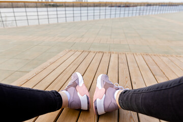 Womens sports shoes on wooden planks. White soles of pink sneakers. View from above