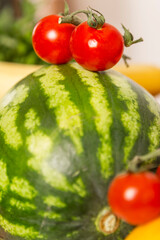 Watermelon and cherry tomatoes. Vegetables and fruits on the table. Healthy food and vegetarianism. Close-up. Selective focus. Vertical.