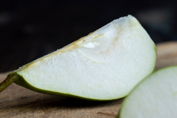 Ripe green pear cut into pieces on the table