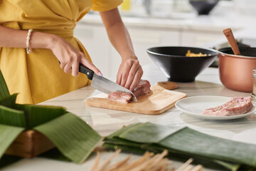 Woman Cutting Seasoned Pork in Pieces