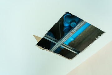 Close up shot at a big hold on ceiling showing water pipe and pumping system.