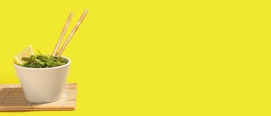 Bowl with healthy seaweed salad on yellow background with space for text © Pixel-Shot