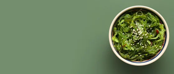 Poster Bowl with healthy seaweed salad on green background with space for text © Pixel-Shot