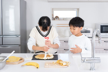 キッチンで料理をしているアジア人の姉弟