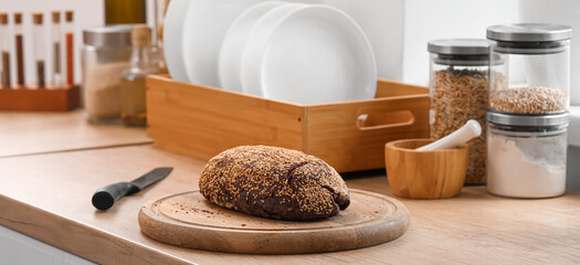 Cutting board with fresh bread and knife on counter in kitchen