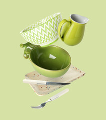 Flying clean dishes and cutlery on green background