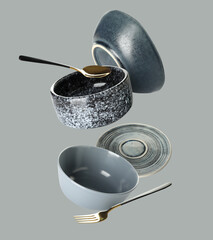 Flying clean dishes and cutlery on grey background