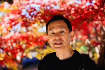 Middle-aged Asian man on a sightseeing tour of the autumn leaves in Kyoto, Japan.
