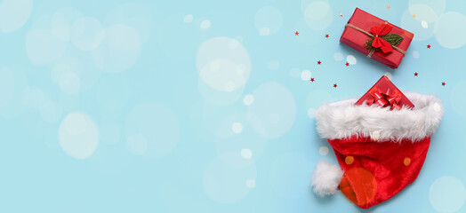 Santa hat and Christmas gifts on light blue background with space for text